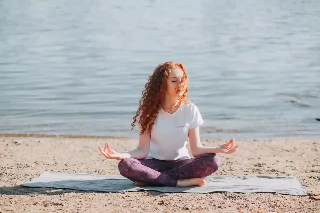 A woman sitting on the beach meditating