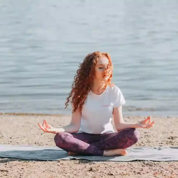 A woman sitting on the beach meditating