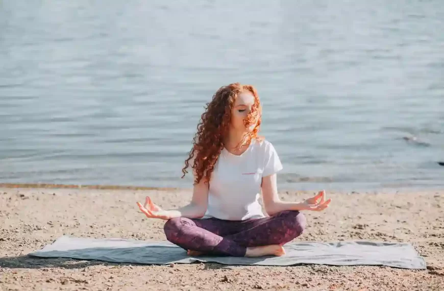 A woman sitting on the beach meditating