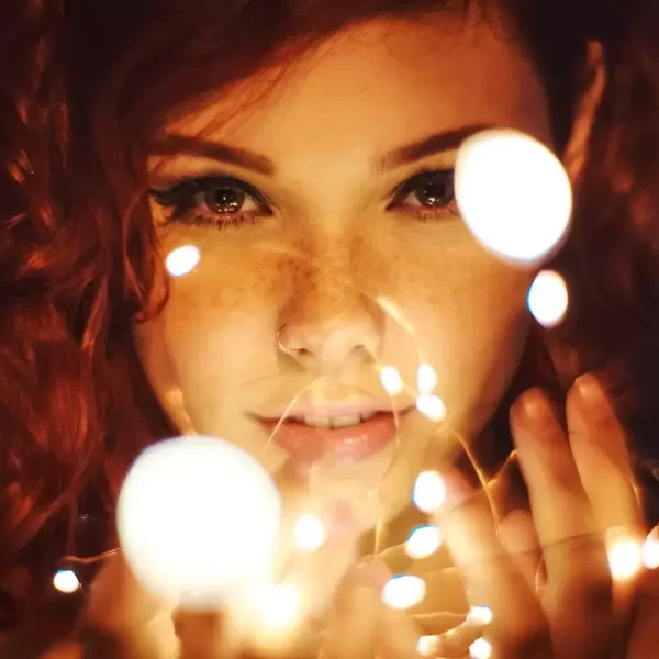 A close up of a girl holding fairy lights