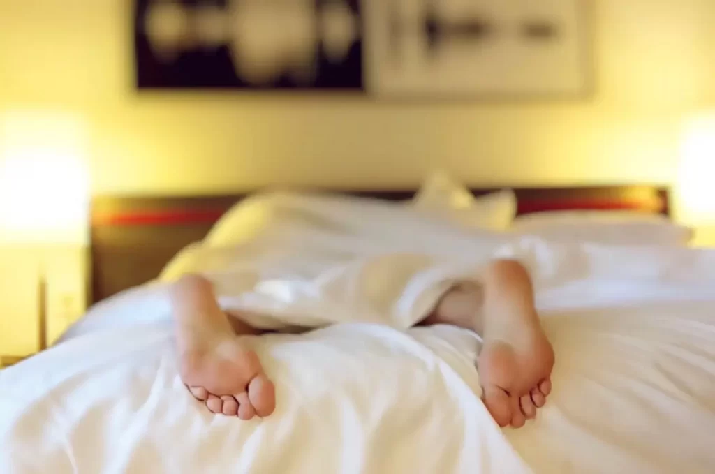 Someone in bed under the sheets with only their feet visible, sleeping