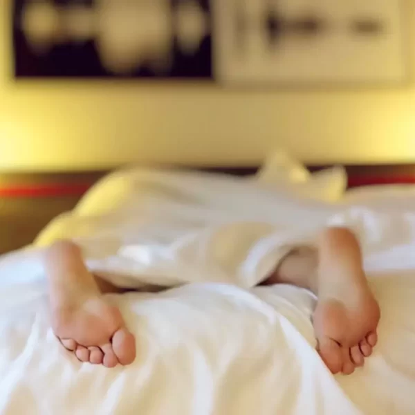 Someone in bed under the sheets with only their feet visible, sleeping