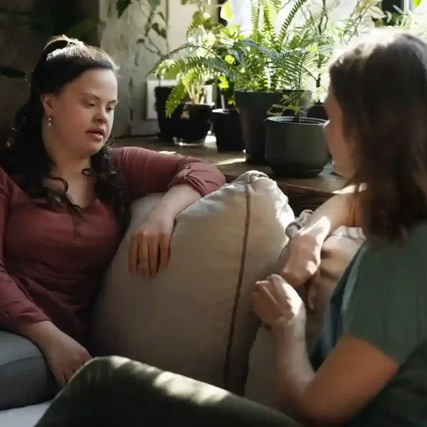 two women sitting on a couch chatting