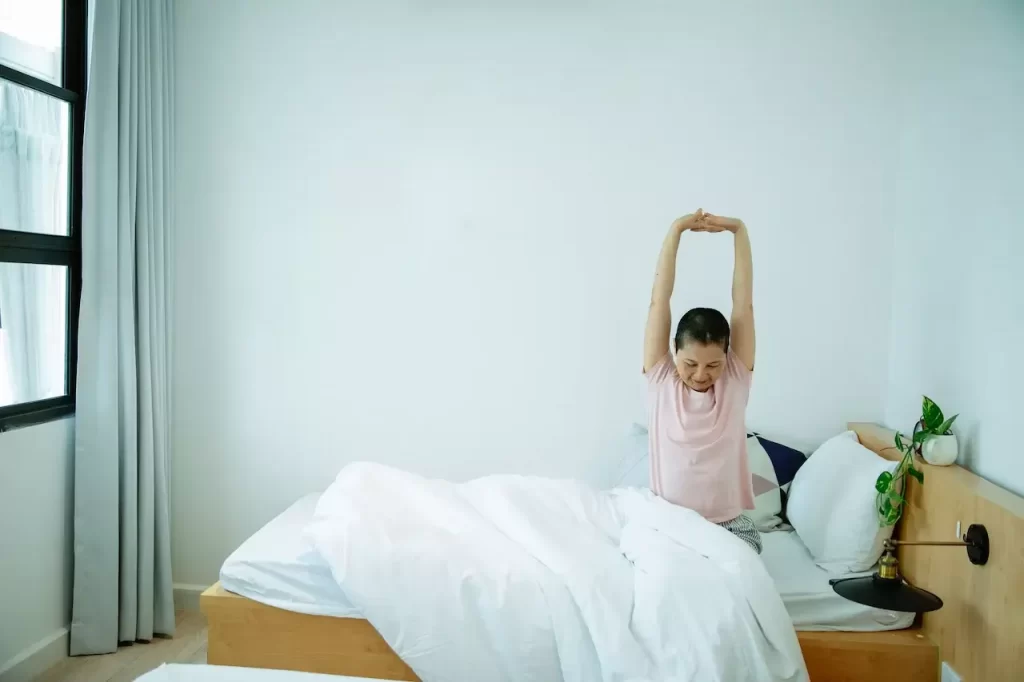 A woman in bed stretching her arms out in the morning