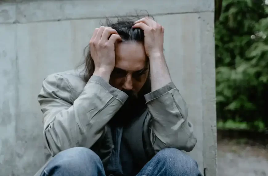 A guy sitting on the ground holding his head