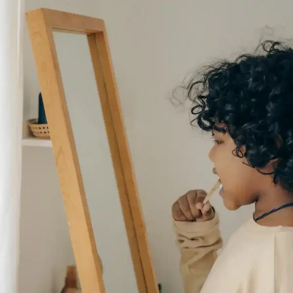 A kid brushing his teeth in front of the mirror