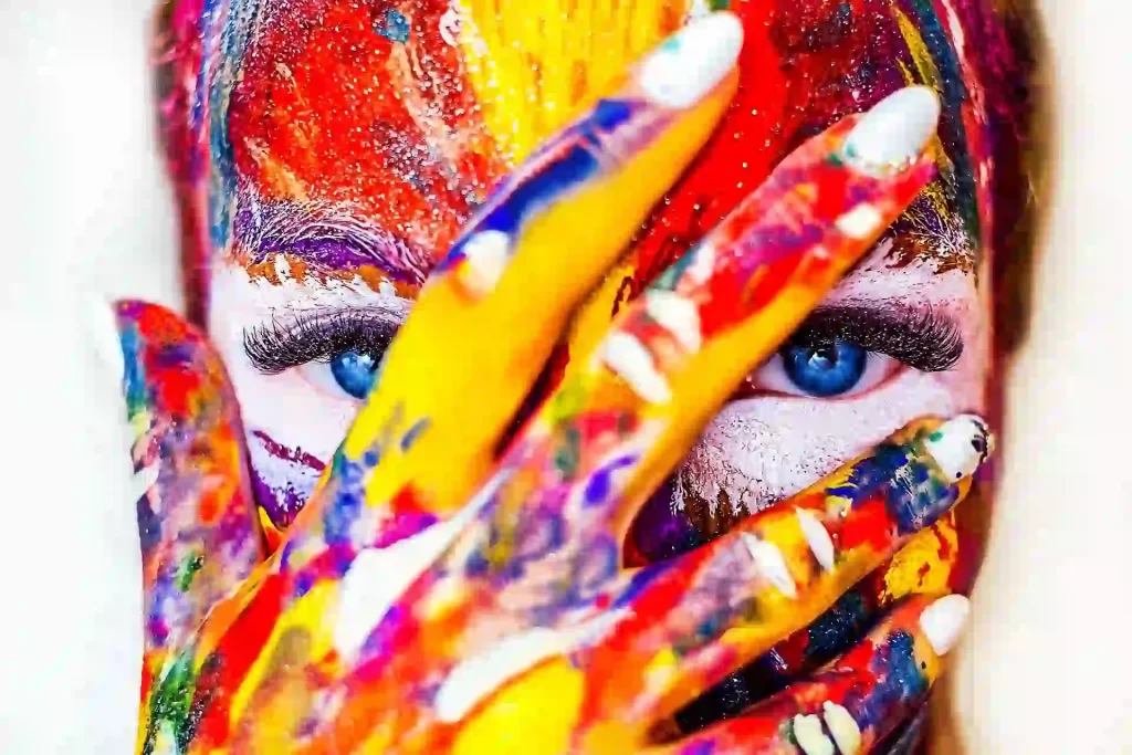 A close up of a girl with paint on her face and hand