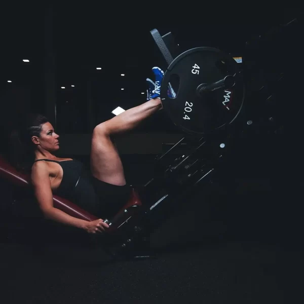 A woman pushing weights with her legs in gym
