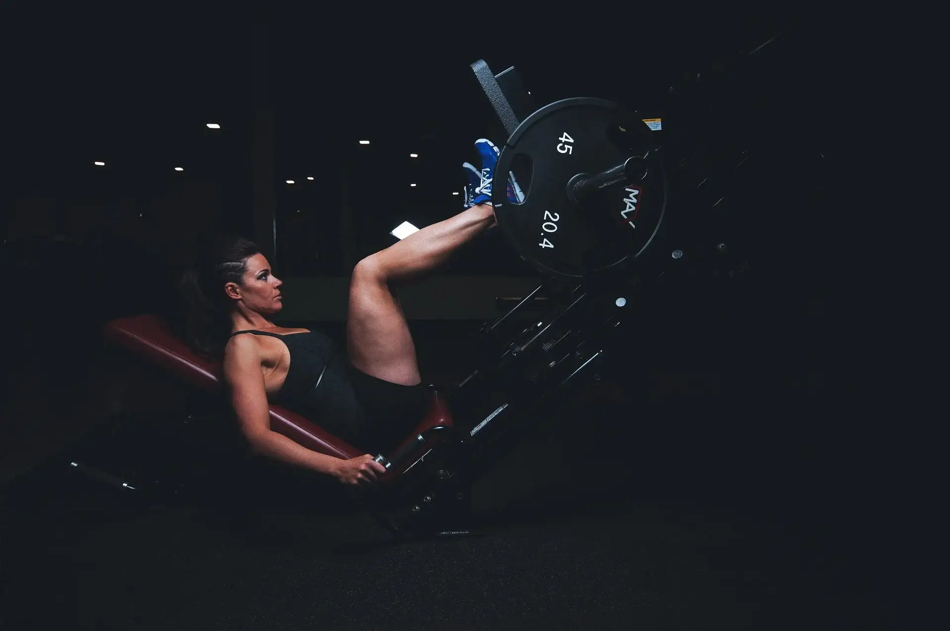 A woman pushing weights with her legs in gym