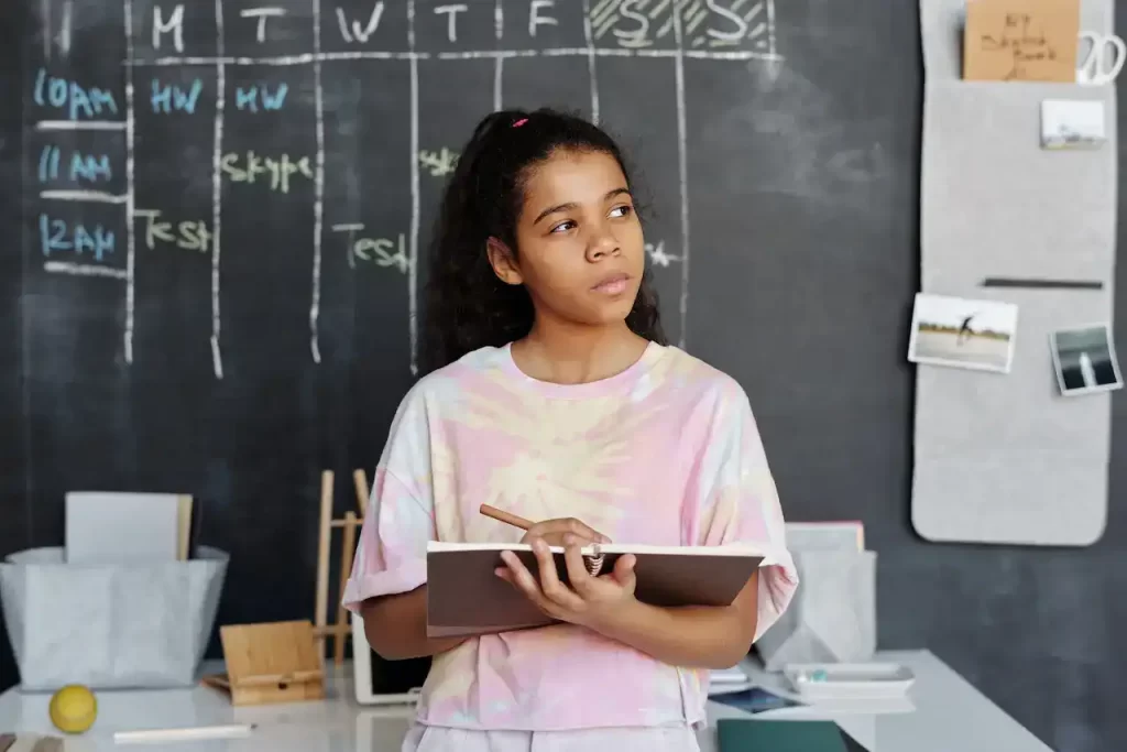 A girl with a writing pad in her hand thinking in class