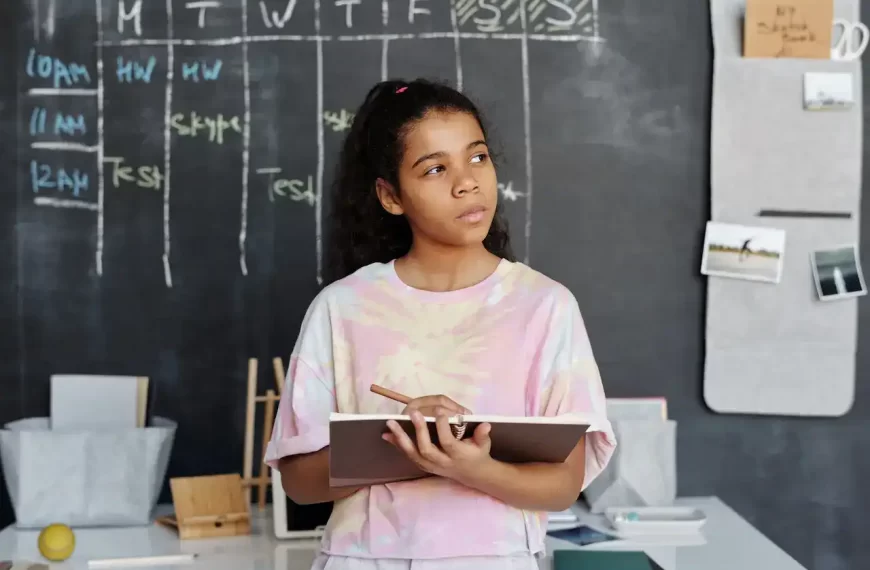 A girl with a writing pad in her hand thinking in class