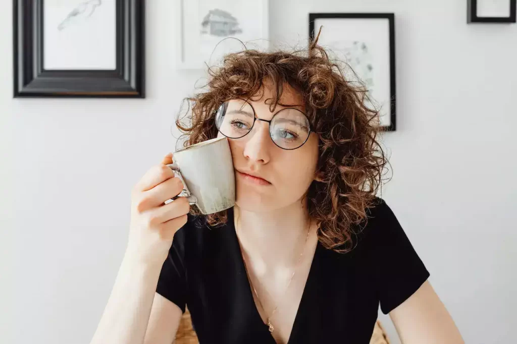 A girl thinking with a cup in hand that's also resting on her cheek