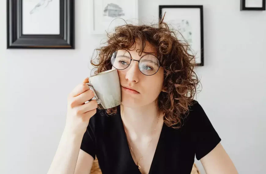 A girl thinking with a cup in hand that's also resting on her cheek