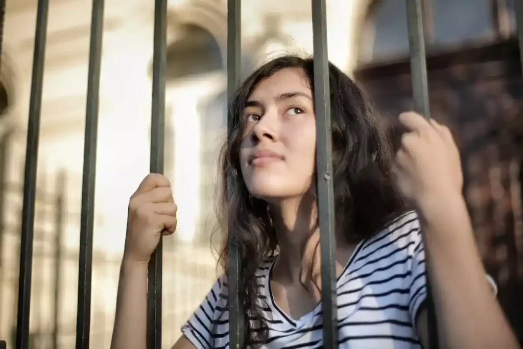 Isolated woman looking away through a fence