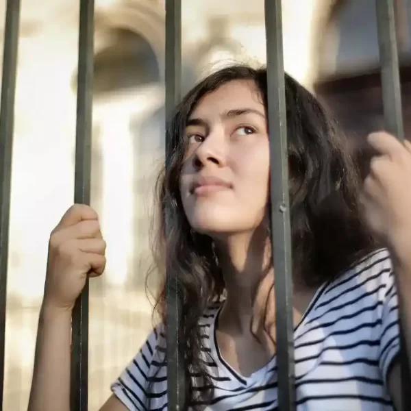 Isolated woman looking away through a fence