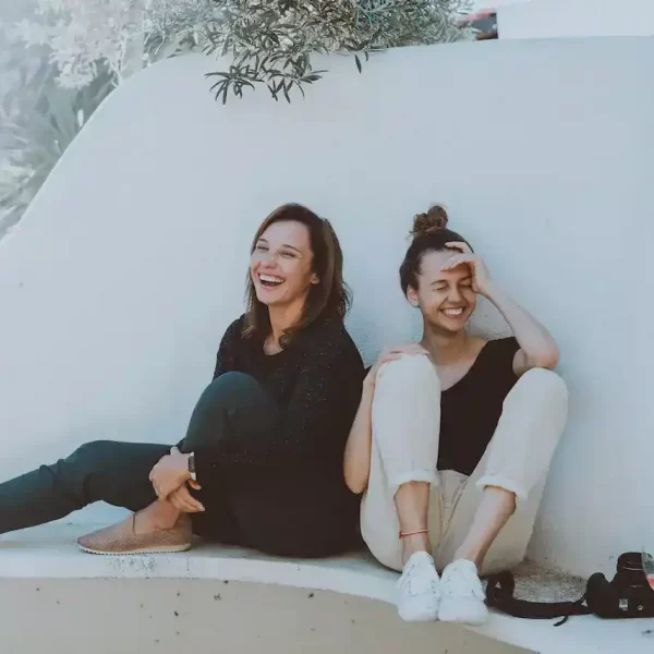 2 women sitting on a white bench laughing