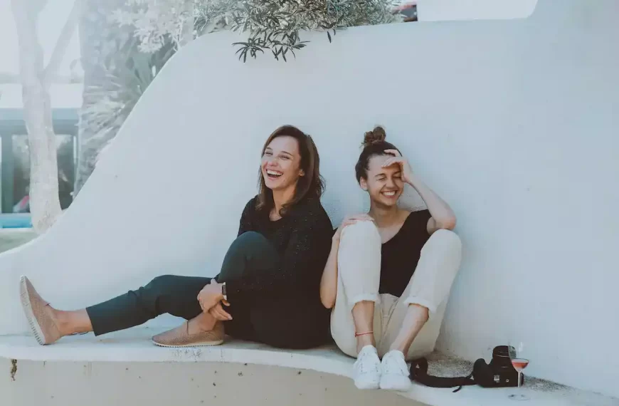 2 women sitting on a white bench laughing