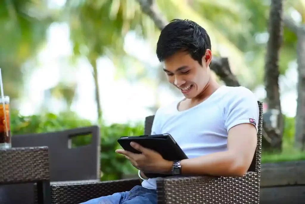 A man sitting on a bench with a tablet in hand smiling