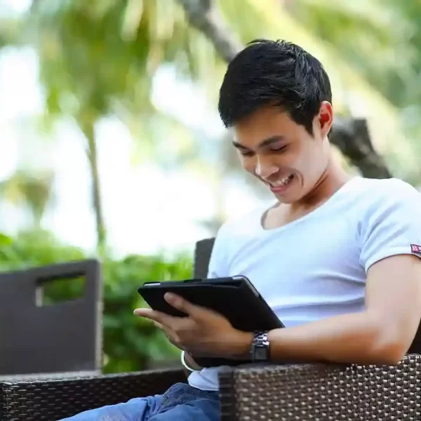 A man sitting on a bench with a tablet in hand smiling