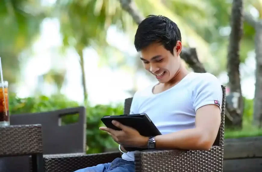 A man sitting on a bench with a tablet in hand smiling