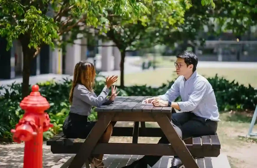 A guy and a girl sitting on a bench and having a conversation