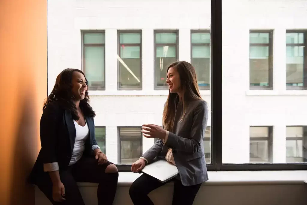 2 woman sitting near glass window and having a conversation