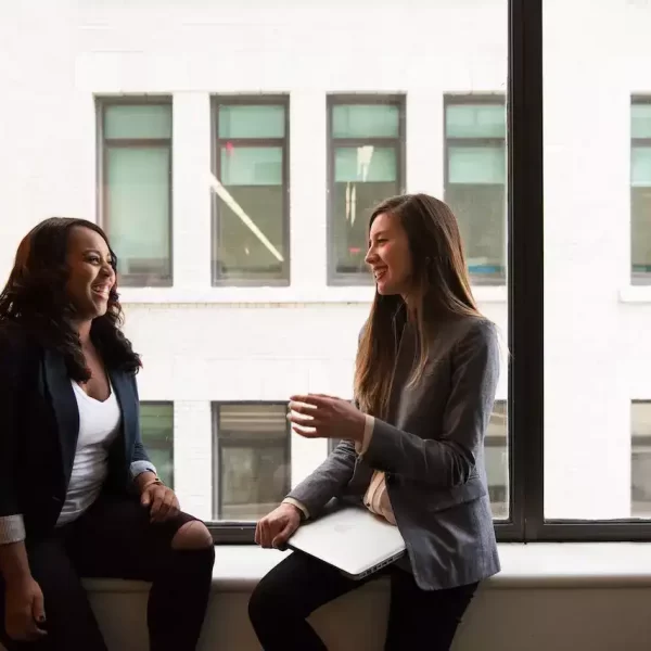 2 woman sitting near glass window and having a conversation