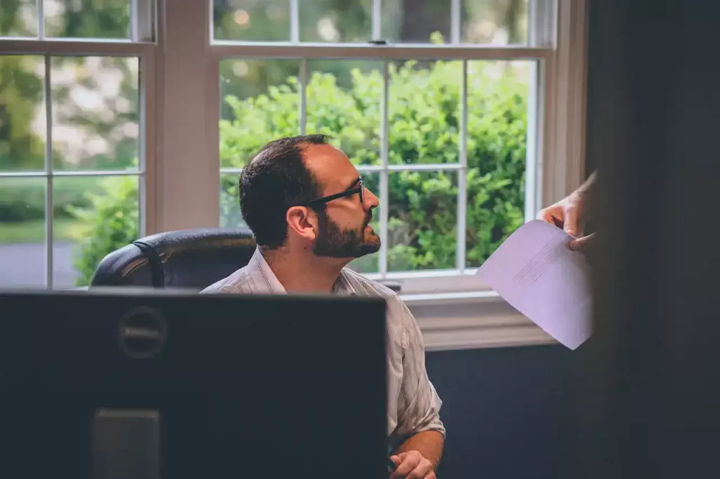 An employee being handed a bunch on papers at the desk