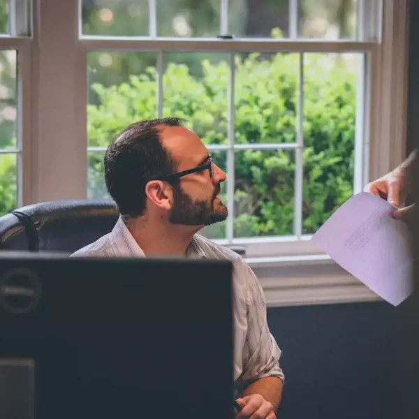 An employee being handed a bunch on papers at the desk