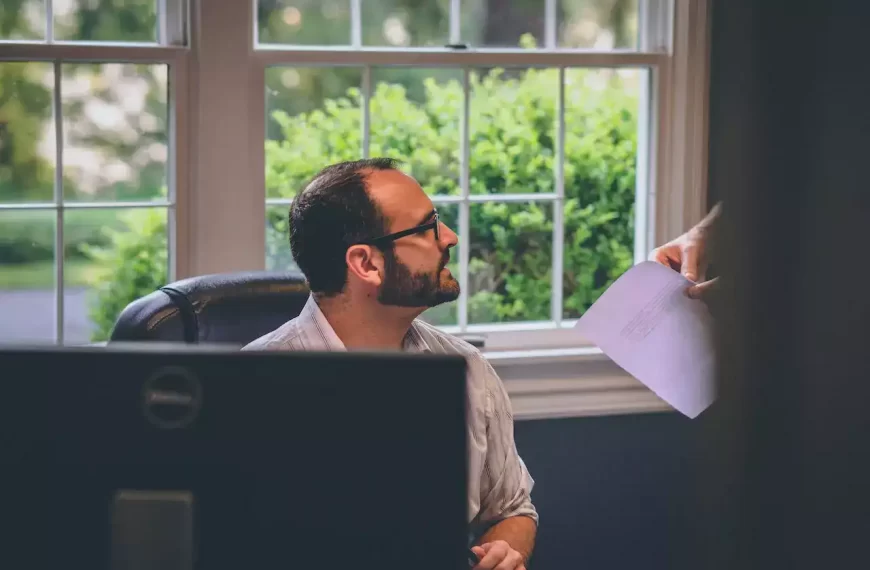 An employee being handed a bunch on papers at the desk