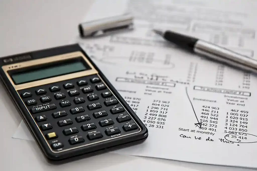 A black calculator near ballpoint pen on a white printed paper