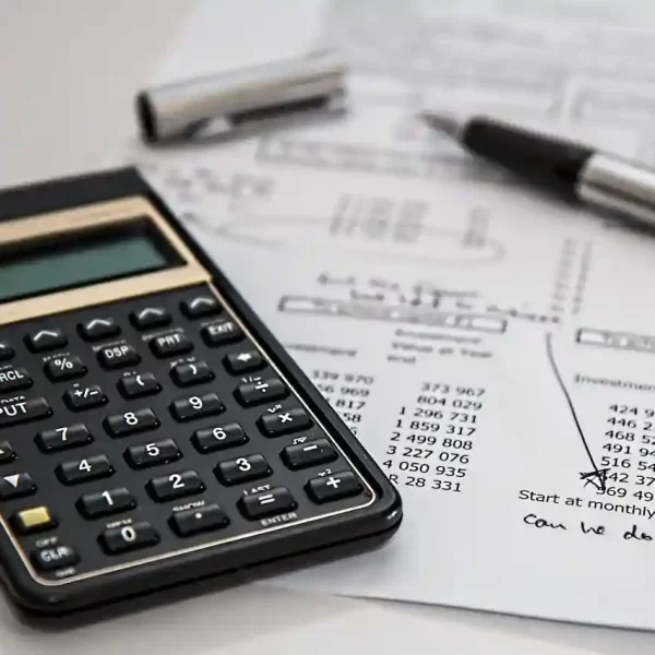 A black calculator near ballpoint pen on a white printed paper