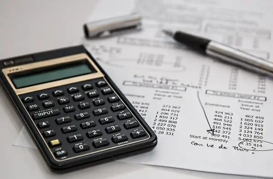 A black calculator near ballpoint pen on a white printed paper