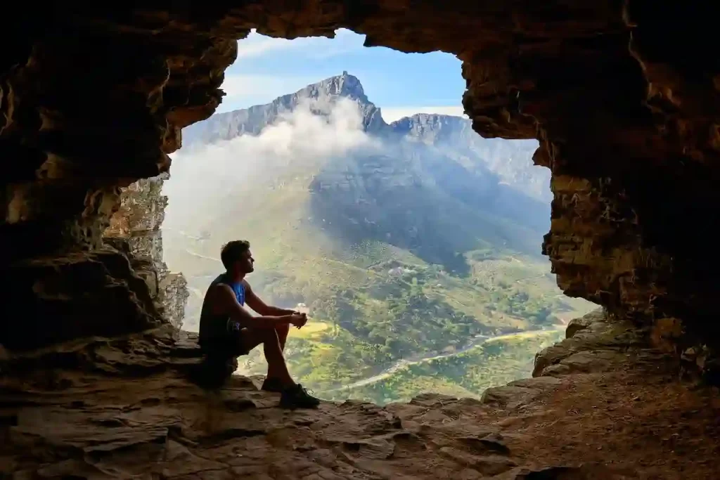 A man sitting in a cave looking over a beautiful scene