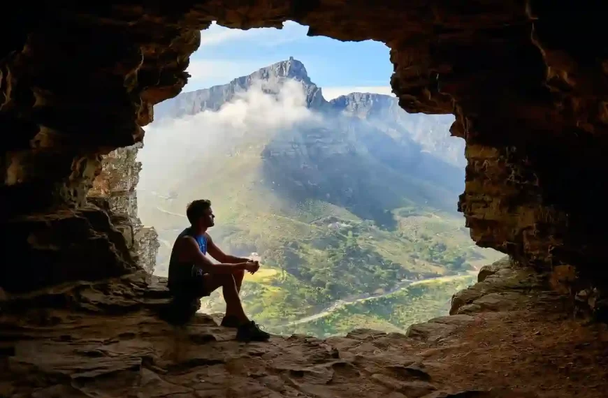 A man sitting in a cave looking over a beautiful scene