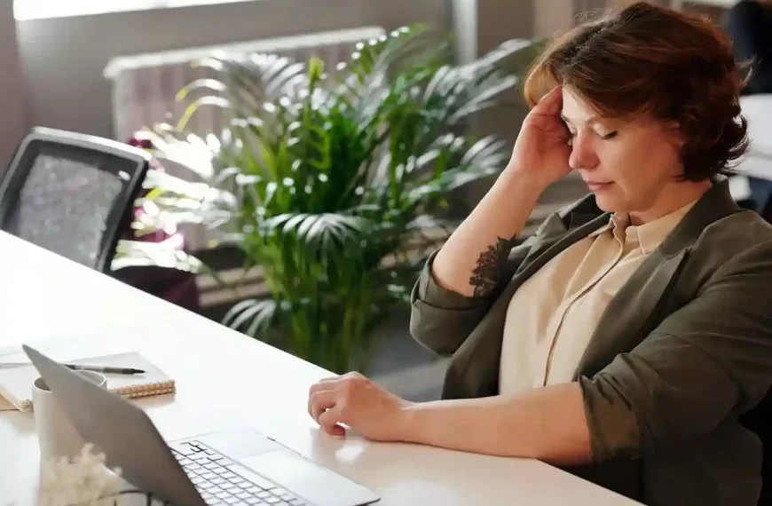 A woman holding her head while sitting in front of the Pc