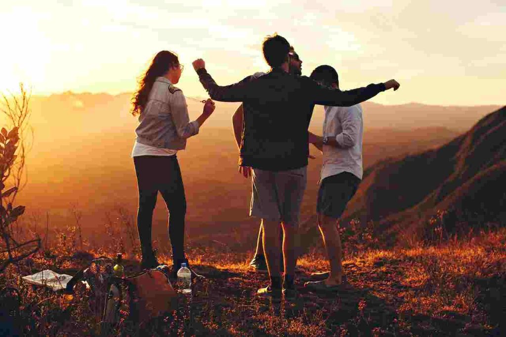 4 friends fancing on top of a mountain and enjoying the sun