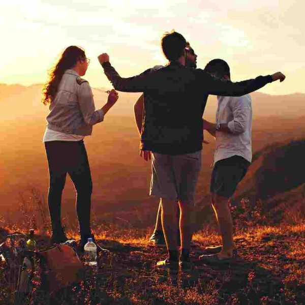 4 friends fancing on top of a mountain and enjoying the sun