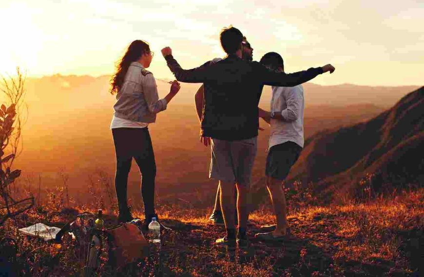 4 friends fancing on top of a mountain and enjoying the sun