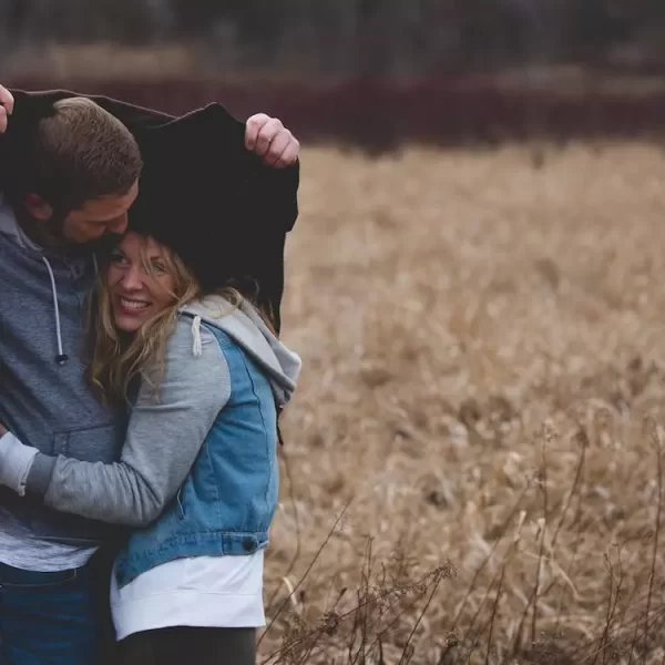 A man and a woman hugging on a brown field