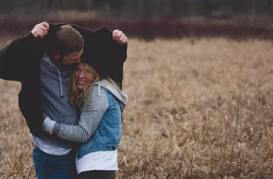 A man and a woman hugging on a brown field