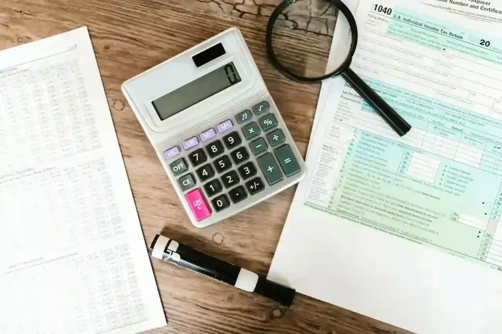 gray calculator and black magnifying glass on brown wooden surface