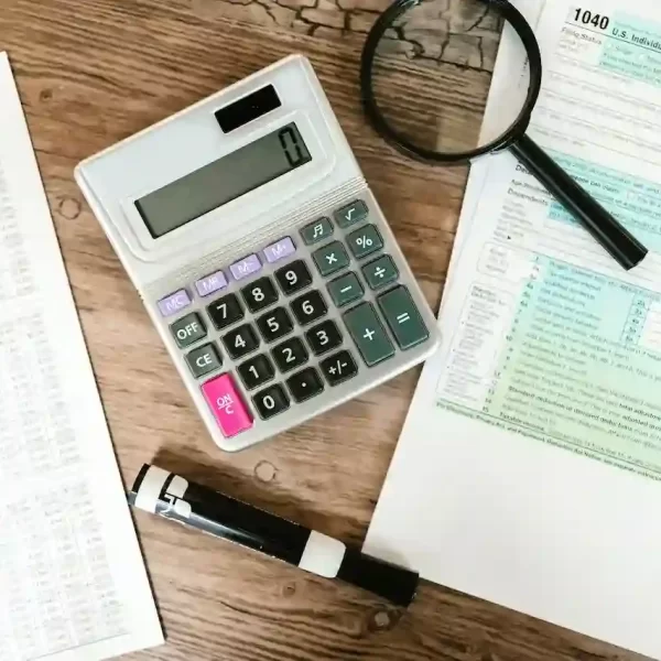 gray calculator and black magnifying glass on brown wooden surface