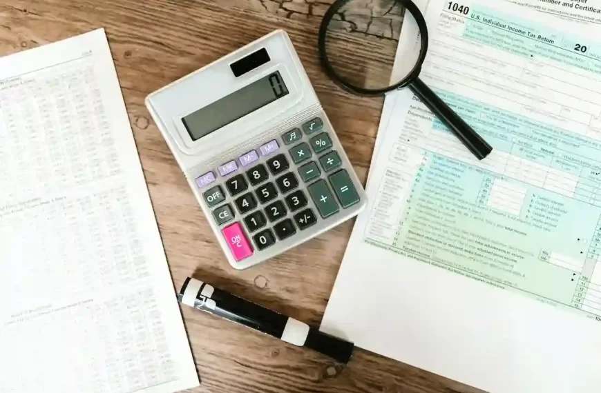 gray calculator and black magnifying glass on brown wooden surface