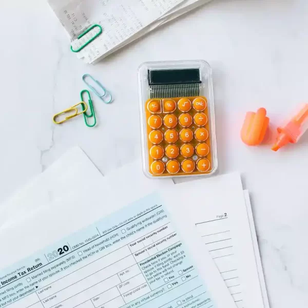 a calculator, highlighter, and bills on a table