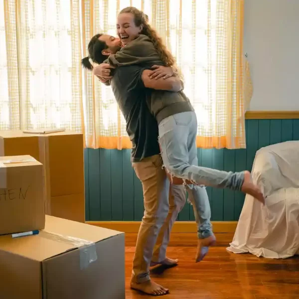 Cheerful couple hugging and unpacking carton boxes