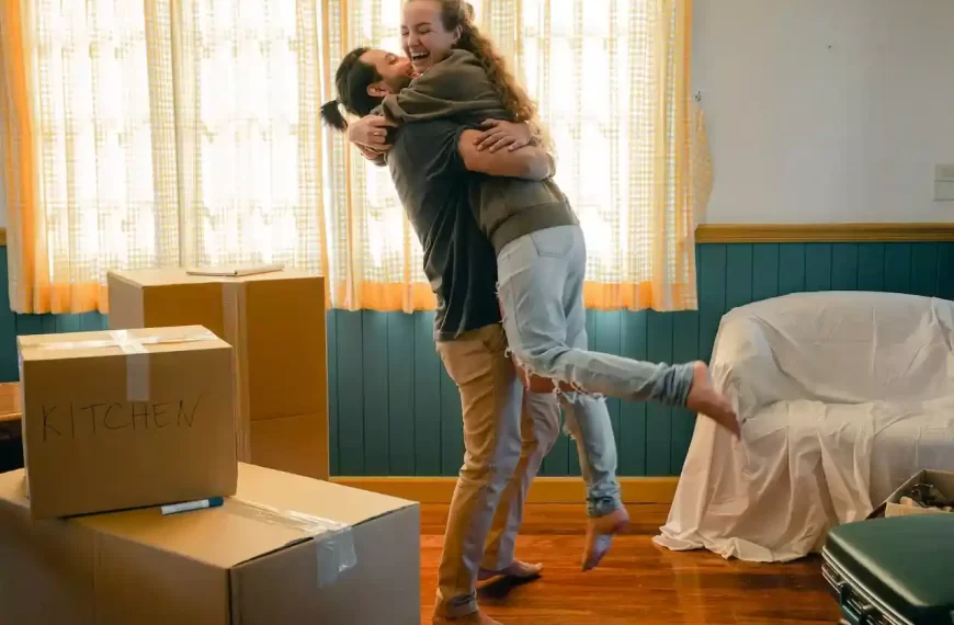 Cheerful couple hugging and unpacking carton boxes