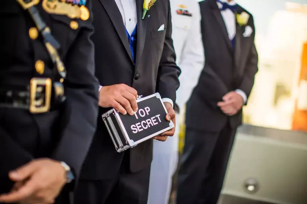 Some high class officers holding a small box that says "TOP SECRET" on it