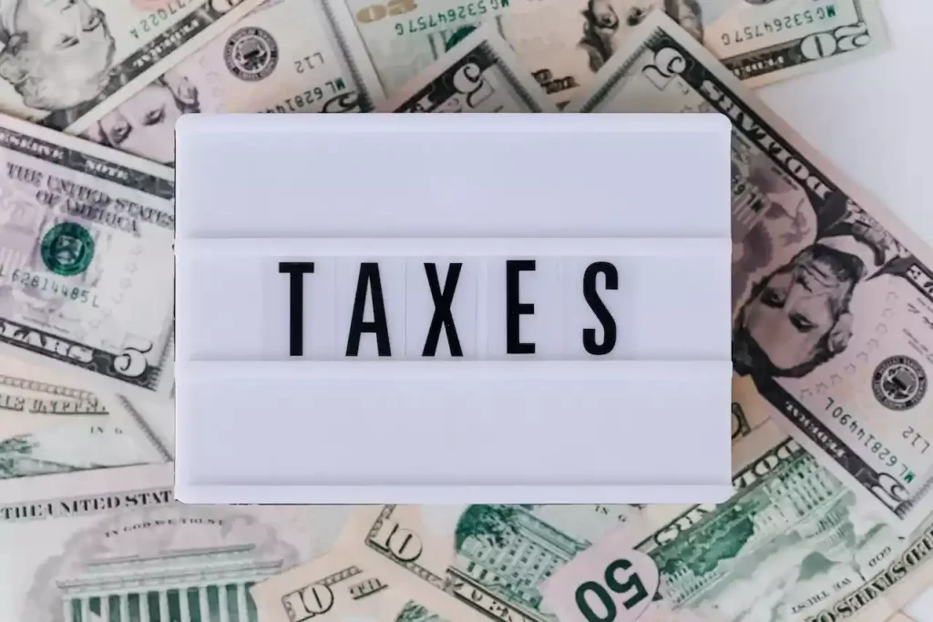 A lightup sign that says "TAXES" with money in the background