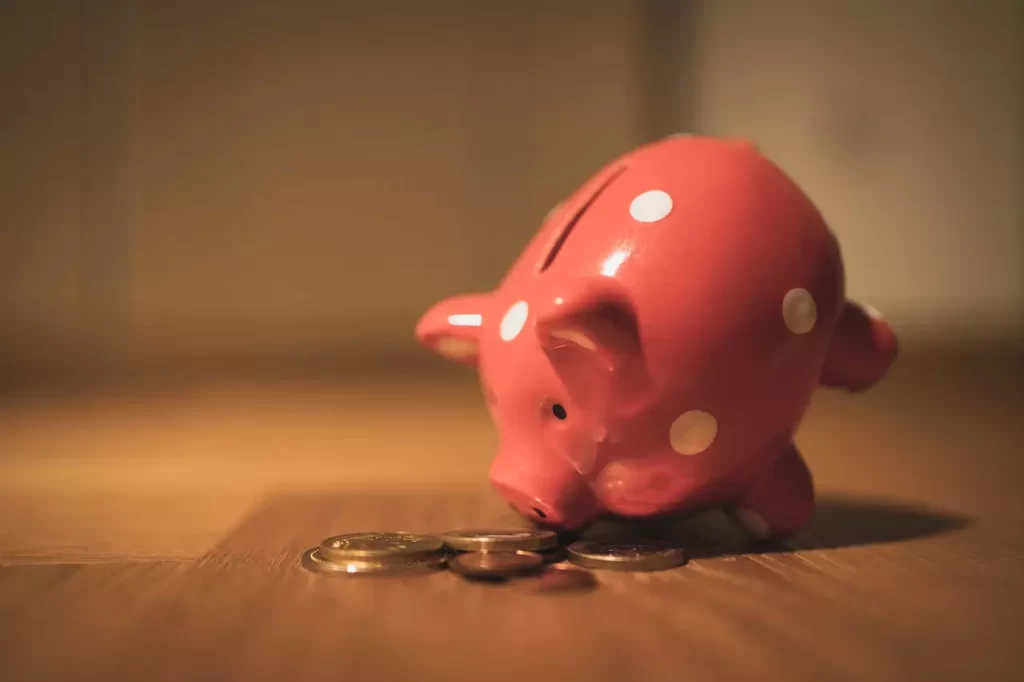 a close up shot of a piggy bank besides coins